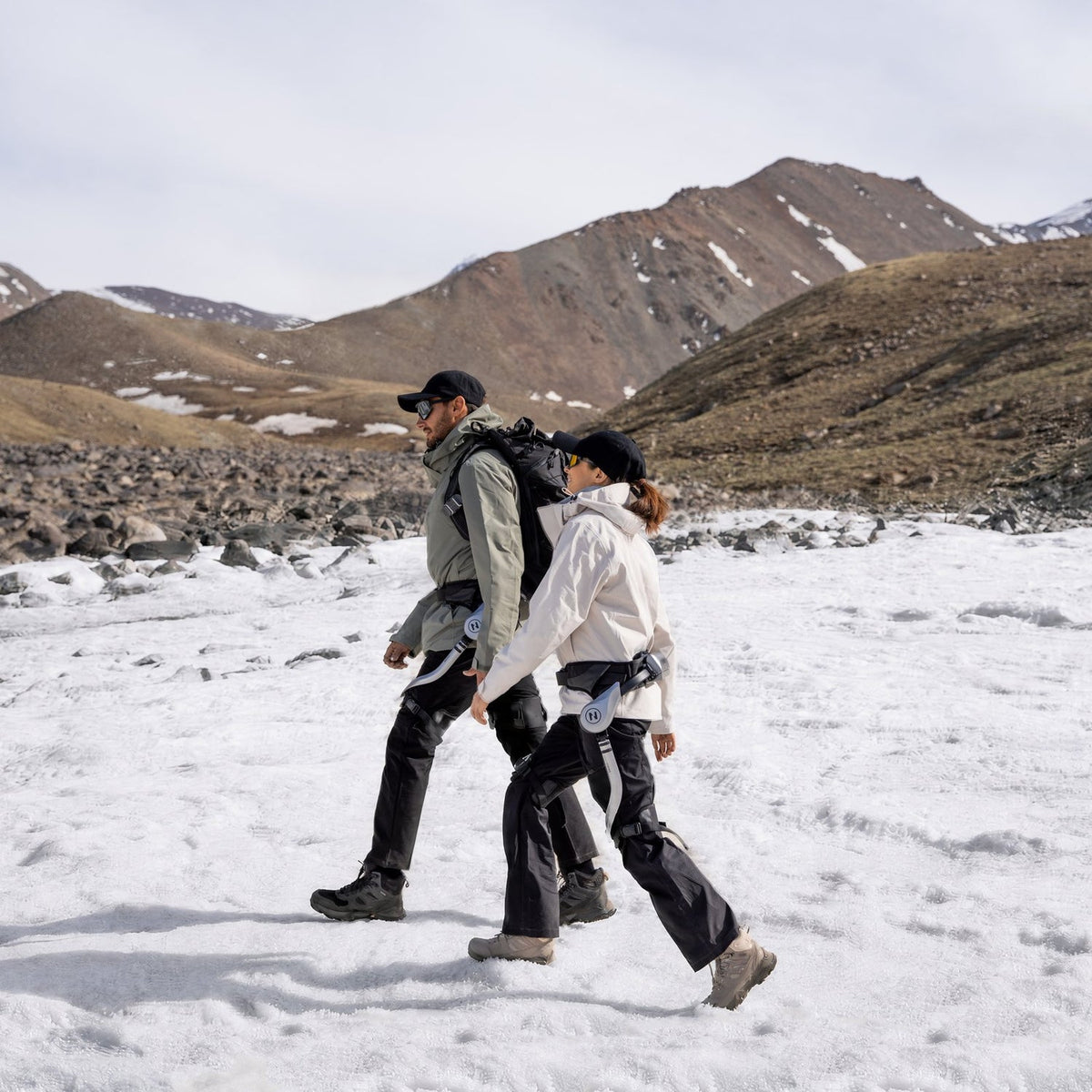 Twee wandelaars met NAVEE EXO S Pro exoskelet steken een sneeuwveld over